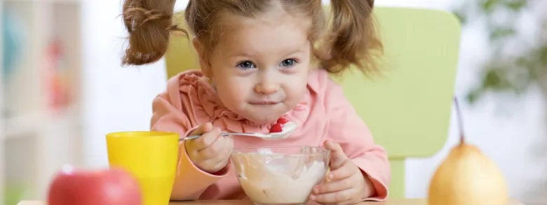 Dívka jí jogurt s ovocem v mrazáku.