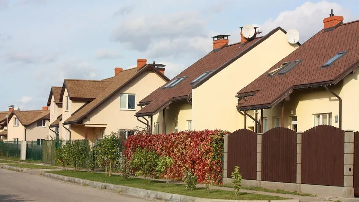 Řada rodinných domů s zahradami a ploty pod širým nebem.