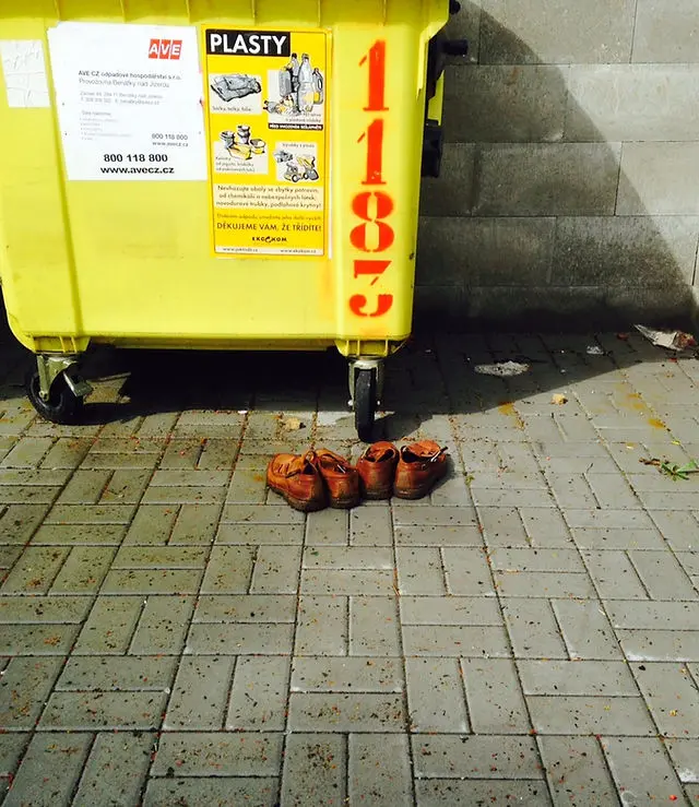 Žlutý kontejner na recyklaci vedle vyhozených bot