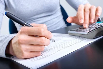 Osoba vyplňuje daňový formulář s kalkulačkou