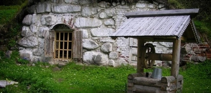 Tradiční kamenný sklep v zemi s dřevěnou studní.