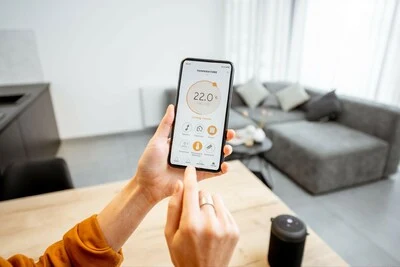Uživatel nastavuje teplotu topení pomocí chytrého telefonu.