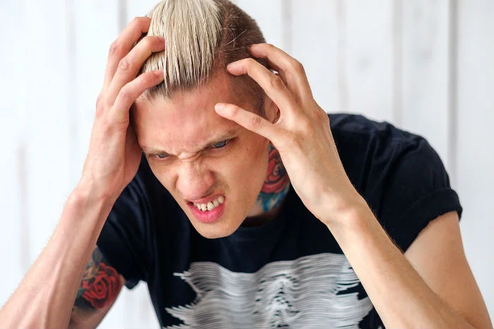 Muž trpící bolestí hlavy s rukama na hlavě