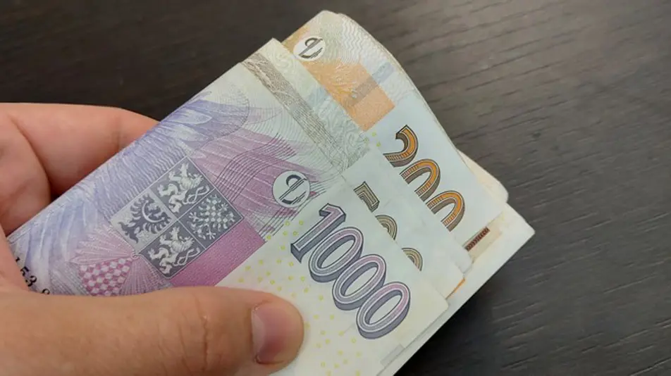 Ruka drží české bankovky jako symbol kauce.