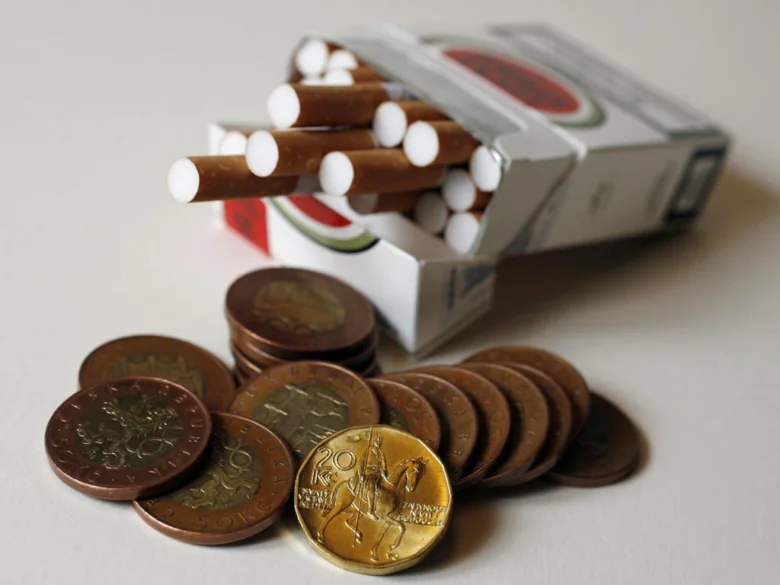 Cigarety s rozsypanými českými mincemi ukazující zdražení.