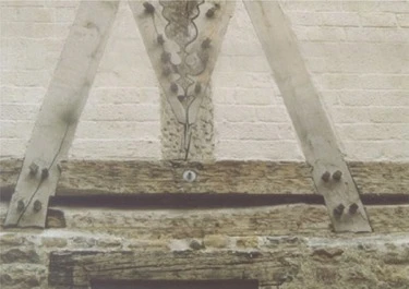 Detail dřevěného rámu v hrázděném domě s kamennou zdí