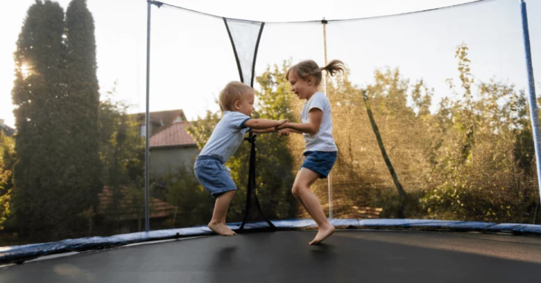 Děti skáčou na trampolín v zahradě s bezpečnostní síťí