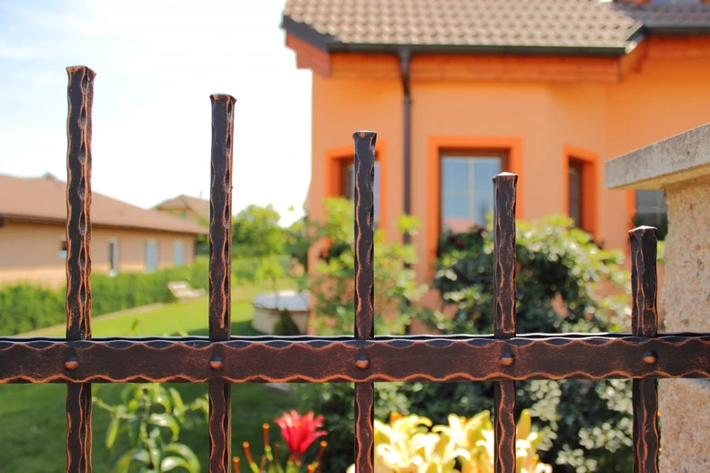 Detail kovového plotu s rustikálním designem