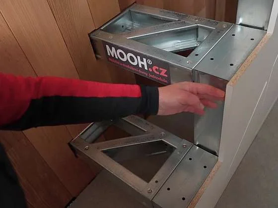 Ruce sestavují kovový rám pro dvouramenné schodiště.