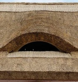 Detail trámové střechy s obloukem v roubené chalupě.