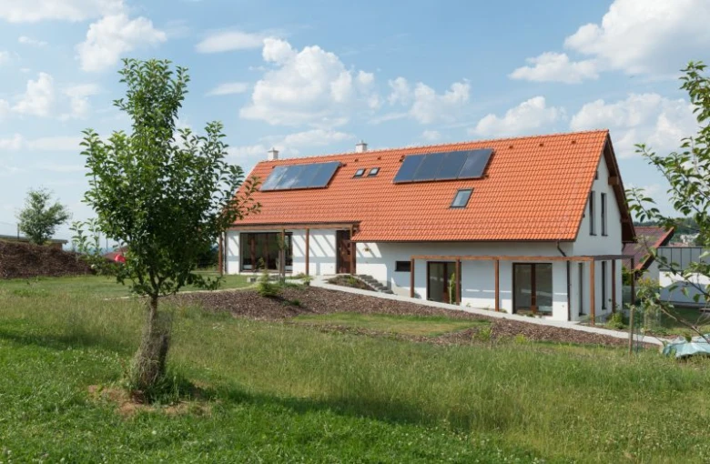 Moderní dům ve svahu s solárními panely na střeše.