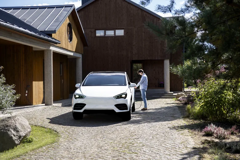 Elektrický vůz nabíjený před moderním domem