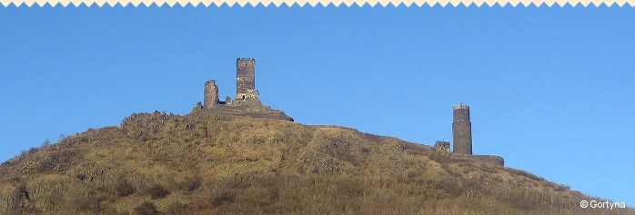 Zřícenina hradu na vrcholu kopce Říp pod modrou oblohou.