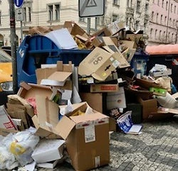 Hromada recyklovatelného odpadu z kartonu a plastu na ulici.