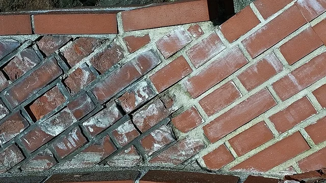 Detail červené klinkerové zdi s viditelnými spárami malt.