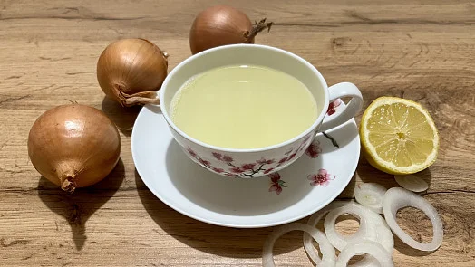 Čaj z cibule s citronem na dřevěném podkladu.