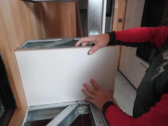 Člověk montuje bílou desku na kovový rám schodiště.